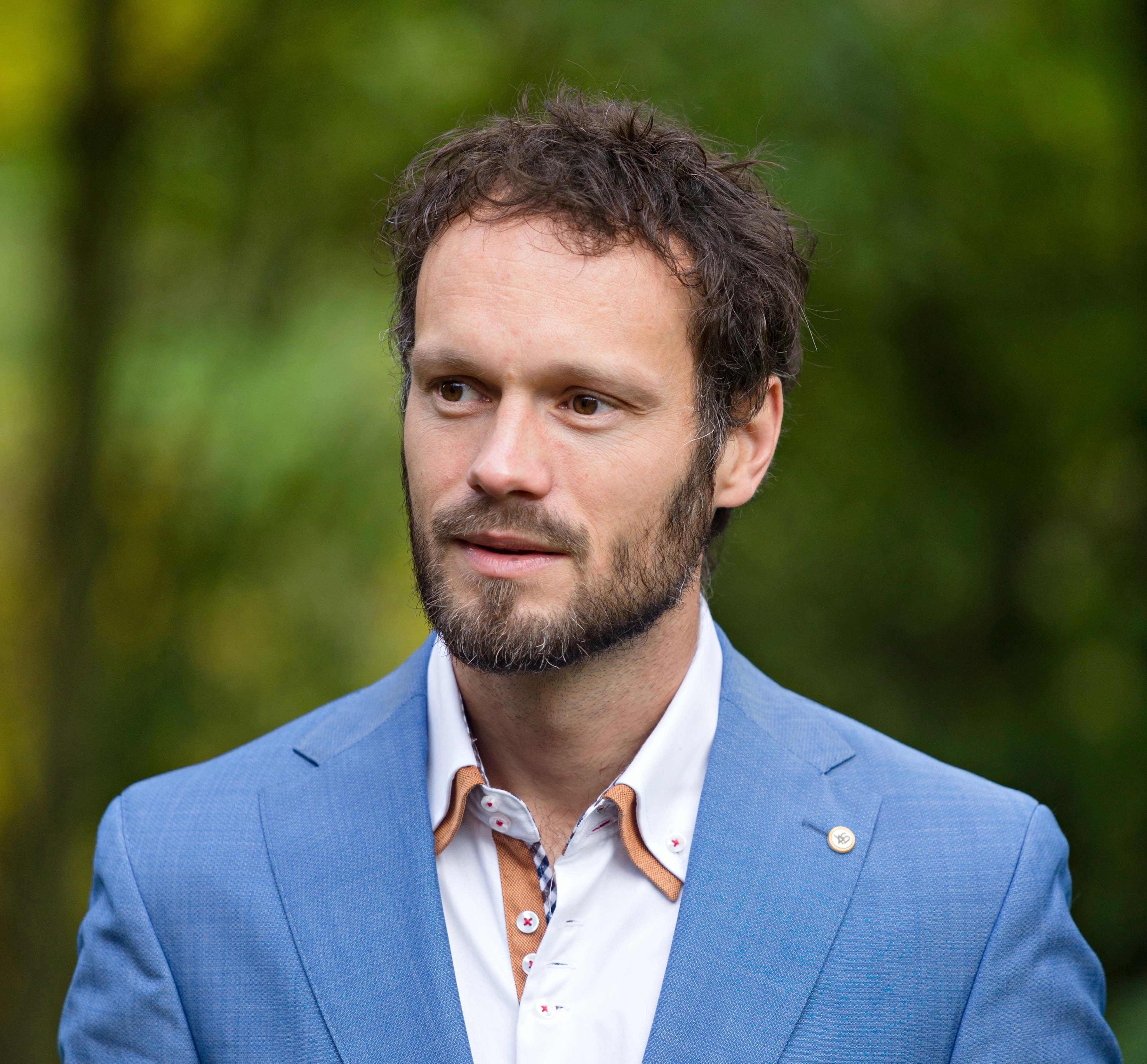 David van Elk in een blauw colbert, gefotografeerd buiten